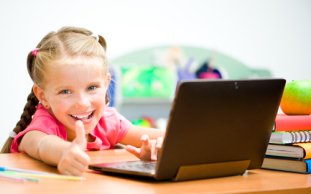 Image of student using Chromebook and giving a thumbs up